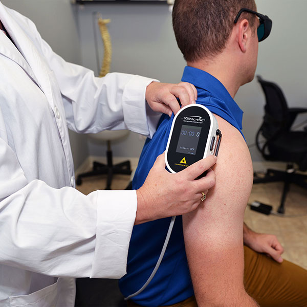Man receiving Theralase cold laser therapy on shoulder